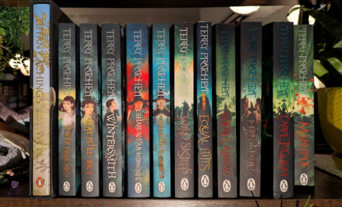 A row of books by Terry Pratchett; the Tiffany Aching series and the Witches series.