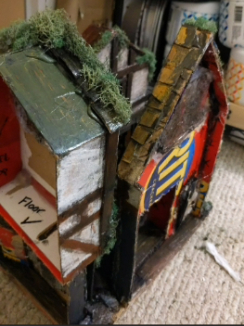 The back of the minature scene. There is exposed cardboard as well as uncovered hot glue and unfinished areas of paint.