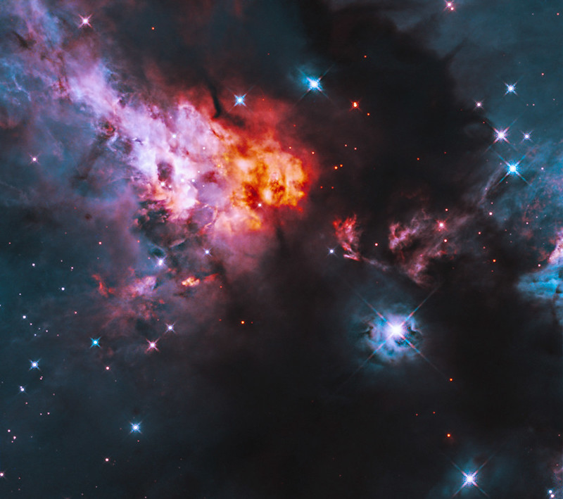 A region of space with bright red and blue cloudy areas, and many bright stars.